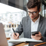 muskarac-pise-laptop-telefon