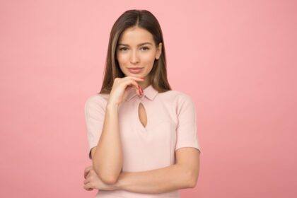 Devojka u roze uniformi pozira ispred roze pozadine