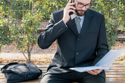 muskarac-telefonira-i-pregleda-dokumenta