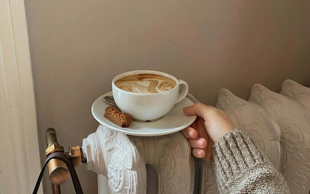 Osoba stavlja šolju kafe na radijator