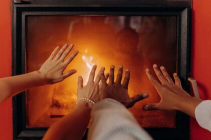 Ljudi greju ruke ispred kamina