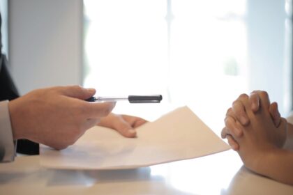 Osoba pruža drugoj osobi papir i olovku