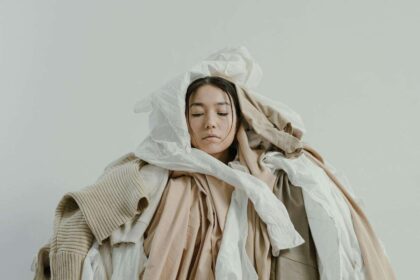 Devojka prekrivena gomilom odeće