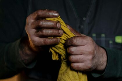 Čovek drži krpu prljavim rukama.