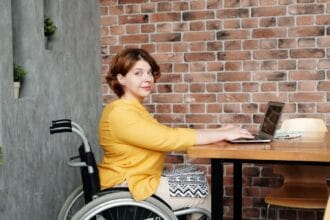 Žena u kolicima radi na laptopu