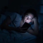 Žena u krevetu gleda mobilni