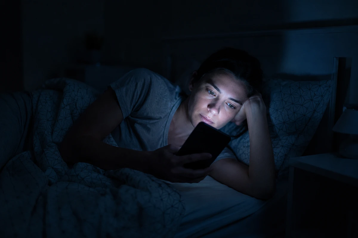 Žena u krevetu gleda mobilni