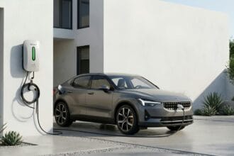 Električni automobil priključen na zidnu stanicu za punjenje ispred moderne kuće