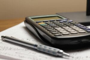 Kalkulator i hemijska olovka na papiru sa matematičkim proračunima