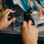 Ruke drže odvijač i odvijaju šraf na metalnom mehaničkom sklopu robota
