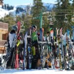 Grupa ljudi okupljena oko ski opreme na snežnom ski centru.