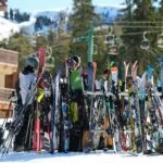 Grupa ljudi okupljena oko ski opreme na snežnom ski centru.