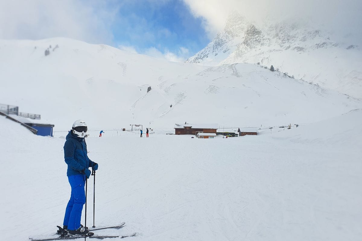 • N2 portal Skijaš zastaje da uživa u pogledu na snegom prekrivene planine pod vedrim plavim nebom na ski centru.